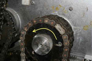 Le sens de rotation de cette motorisation par chaîne est indiqué par la flèche en jaune. On remarque une maille d’accouplement qui réunit les deux parties de la chaîne. Cette maille d’accouplement a été posée à l’envers. Comme l’ouverture de la maille d’accouplement est face à la direction du mouvement de la chaîne,  la moindre interférence avec un obstacle quelconque risque de la faire se détacher avec les conséquences que cela entraînerait.
